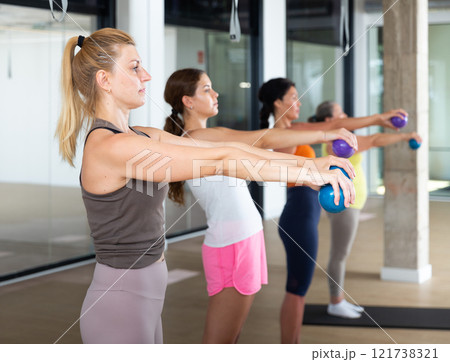 Women performing set of exercises with two small pilates balls Women performing set of exercises with two small pilates balls 121738321