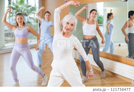 Group of active women practicing energetic dance in modern dance studio 121738477