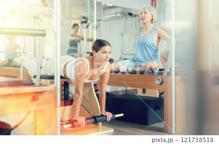 Woman pilates stretching sport in reformer bed 121738518