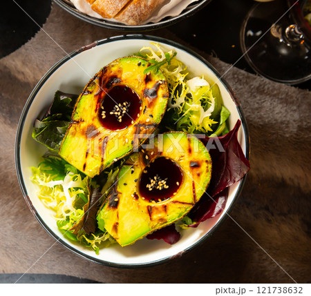 Grilled avocado with ponzu sauce and greens Grilled avocado with ponzu sauce and greens 121738632