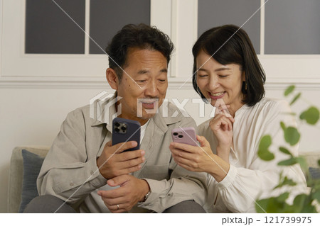 夜のリビングでスマホを使う熟年夫婦 夜のリビングでスマホを使う熟年夫婦 121739975