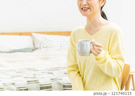 ベッドでコーヒーを飲むミドル女性 121740115