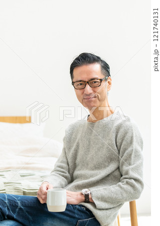 ベッドルームでコーヒーを飲むミドル男性 121740131