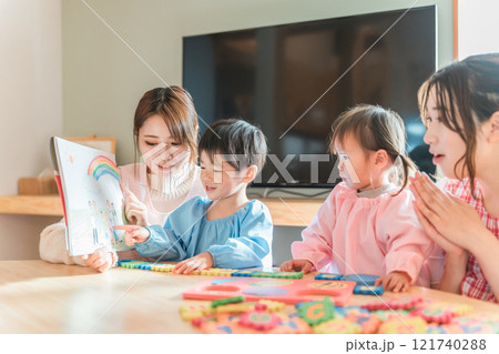 保育園・幼稚園・託児所・保育所で園児に紙芝居・絵本を読み聞かせする女性保育士・保母さん・シッター 121740288