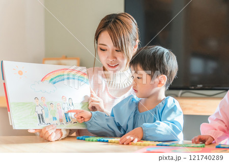 保育園・幼稚園・託児所・保育所で園児に紙芝居・絵本を読み聞かせする女性保育士・保母さん・シッター 121740289