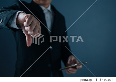 A man in a suit stands with his thumbs down, showing dissatisfaction, bad service, bad things, bad feelings. A man in a suit stands with his thumbs down, showing dissatisfaction, bad service, bad things, bad feelings. 121740301