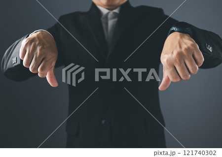 A man in a suit stands with his thumbs down, showing dissatisfaction, bad service, bad things, bad feelings. A man in a suit stands with his thumbs down, showing dissatisfaction, bad service, bad things, bad feelings. 121740302