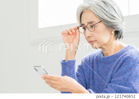 老眼鏡でスマホを見るシニア女性 老眼鏡でスマホを見るシニア女性 121740652