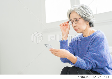 老眼鏡でスマホを見るシニア女性 老眼鏡でスマホを見るシニア女性 121740653