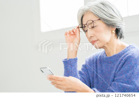 老眼鏡でスマホを見るシニア女性 121740654