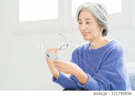 老眼鏡でスマホを見るシニア女性 老眼鏡でスマホを見るシニア女性 121740656