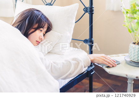 目覚ましの音で起きる女性 121740929