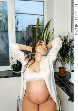 Pregnant Woman Relaxing with Lingerie by the Window Pregnant Woman Relaxing with Lingerie by the Window 121741041