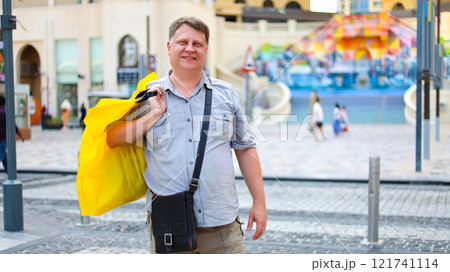 Man with shopping bag in summer clothes on city street on hot day Man with shopping bag in summer clothes on city street on hot day 121741114