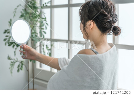 鏡を見ながら化粧品・コスメでスキンケアする日本人女性（美容・美肌・保湿・化粧・メイク） 121741206