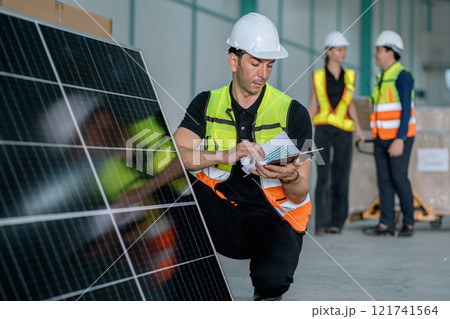 man in a yellow vest is looking at a tablet while standing next to a solar pan man in a yellow vest is looking at a tablet while standing next to a solar pan 121741564