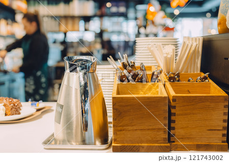 カフェのカウンターに並ぶステンレスポットと木製カトラリーケース 121743002