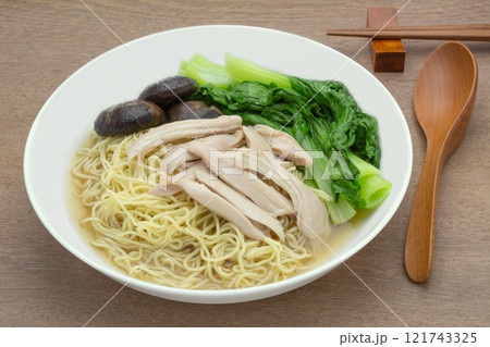 homemade style egg noodles and chicken with clear soup in a ceramic bowl on wooden table, close up. asian food concept. homemade style egg noodles and chicken with clear soup in a ceramic bowl on wooden table, close up. asian food concept. 121743325