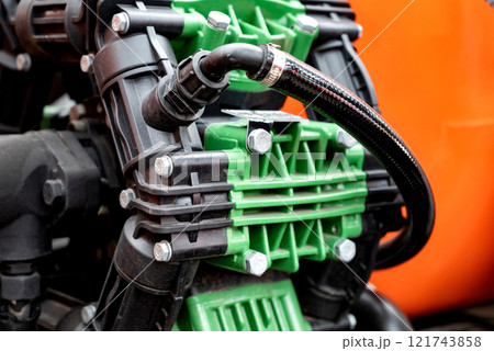 Close-up of industrial pump with green and black components, orange background. Close-up of industrial pump with green and black components, orange background. 121743858