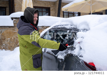Person Clearing Snow from Car in Winter Landscape Person Clearing Snow from Car in Winter Landscape 121744011