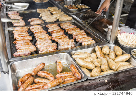 Close-up of the vendors grilling Taiwanese sausage and sticky rice (glutinous rice) sausage in the night market in Taiwan. This is one of the street snacks popular among tourists in Taiwan. Close-up of the vendors grilling Taiwanese sausage and sticky rice (glutinous rice) sausage in the night market in Taiwan. This is one of the street snacks popular among tourists in Taiwan. 121744946