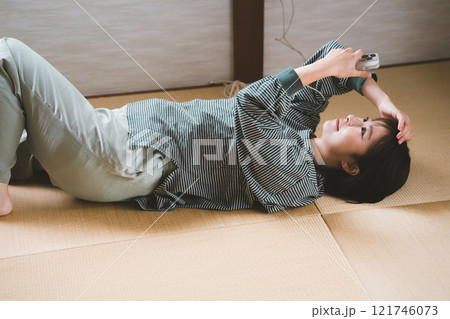 畳でゴロゴロする女性 121746073