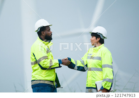 Team of electricians engineer are having a conversation and discussion together at electric generator windmill station. Female and male professional engineers are working at electric wind turbine. Team of electricians engineer are having a conversation and discussion together at electric generator windmill station. Female and male professional engineers are working at electric wind turbine. 121747913