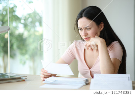 Suspicious asian woman checking receipt at home Suspicious asian woman checking receipt at home 121748385