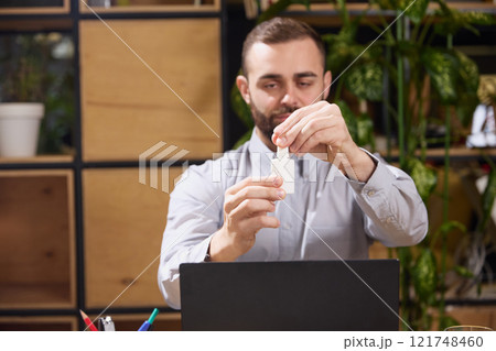 Young man sits at work, and open bottle of nasal spray with negative space to insert your text. Photo with selective focus. 121748460