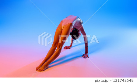 Athlete practices controlled movements, refining posture and precision in pink neon light against gradient blue background. Athlete practices controlled movements, refining posture and precision in pink neon light against gradient blue background. 121748549