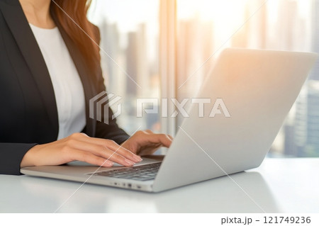 A professional woman is diligently working on her laptop in a modern office environment 121749236