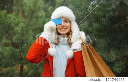 Happy smiling young woman with shopping bag, holding plastic credit bank card in winter, Christmas 121749465