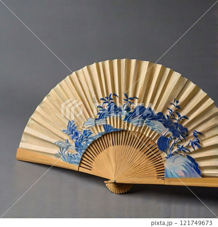 Traditional folding fan with blue floral patterns on beige background.  121749673