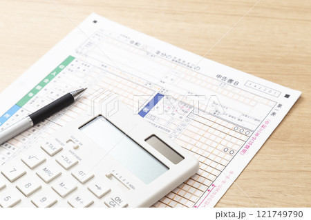 机に置かれた確定申告書類と電卓 121749790