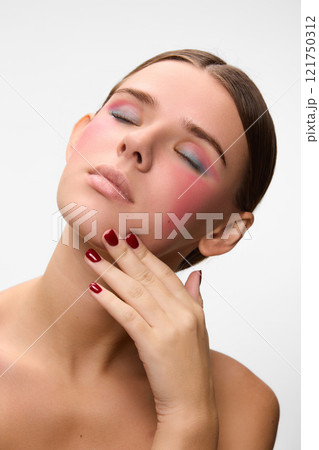 Serene pose with eyes closed, featuring harmonious blend of vivid makeup shades that highlight beautiful woman's features. Serene pose with eyes closed, featuring harmonious blend of vivid makeup shades that highlight beautiful woman's features. 121750312