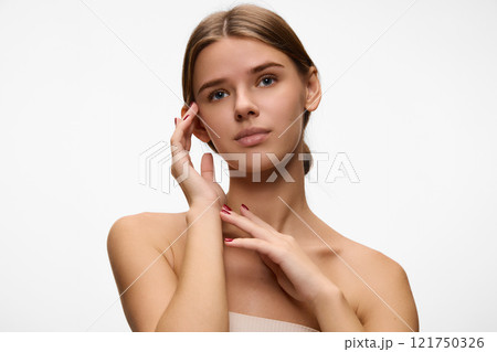 Woman in relaxed pose with hands gently framing her face against white studio background, Emphasizing radiant skin and self-care. Concept of natural beauty. 121750326
