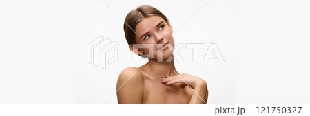 Banner. Woman with dreamy gaze, her hand softly resting on her shoulder against white studio background with negative space. Concept of natural beauty. 121750327