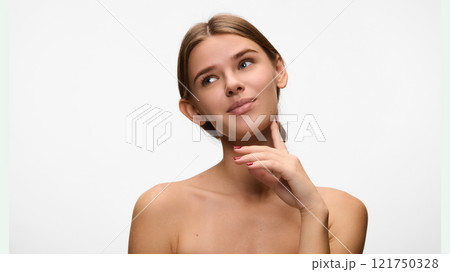 Thoughtful expression as beautiful woman gently touches her chin, representing self-reflection and grace, against white studio background. Concept of natural beauty. Thoughtful expression as beautiful woman gently touches her chin, representing self-reflection and grace, against white studio background. Concept of natural beauty. 121750328