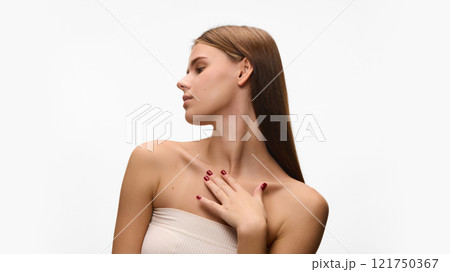 Profile photo of young beautiful woman in white top, showing her smooth, flawless neckline against white studio background. Concept of natural beauty. 121750367