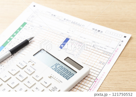 机に置かれた確定申告書類と電卓 121750552