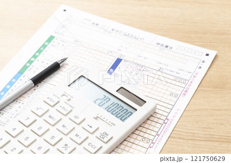 机に置かれた確定申告書類と電卓 121750629