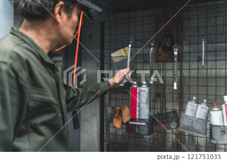 壁掛け工具を整理整頓する自動車整備士・メカニックの男性 121751035