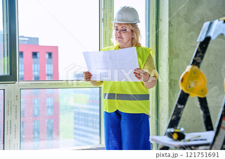 Technical profession woman in protective vest helmet working on construction 121751691