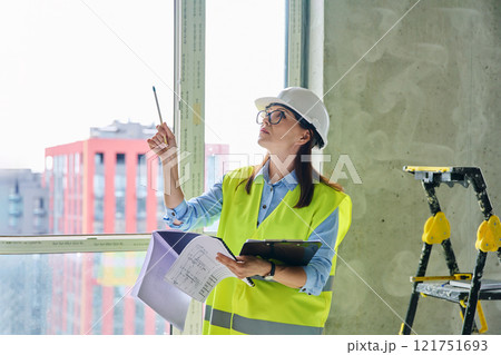 Technical profession woman in protective vest helmet working on construction 121751693