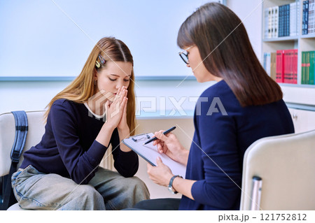 Sad serious teenage student girl talking with female school counselor, teacher 121752812