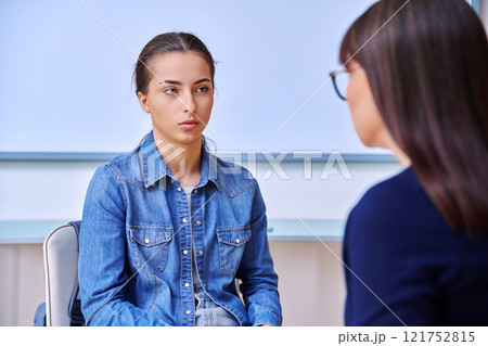 Female psychologist talking with teenage girl inside educational building Female psychologist talking with teenage girl inside educational building 121752815
