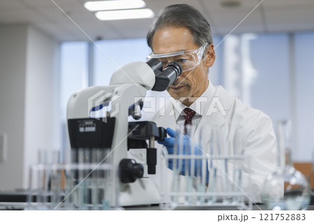 顕微鏡で作業をする白衣を着た60代の男性 顕微鏡で作業をする白衣を着た60代の男性 121752883