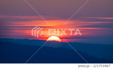 Colorful sunset over the forested hills. 121753967