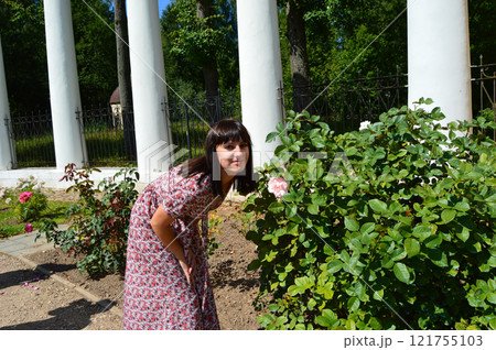 Joyful Young Woman Admiring a Beautiful Rose in Bloom 121755103