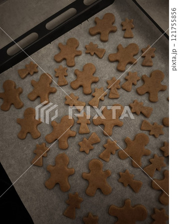 Gingerbread men and comets cookies baking on a tray and paper, ready for the holiday season christmas Gingerbread men and comets cookies baking on a tray and paper, ready for the holiday season christmas 121755856